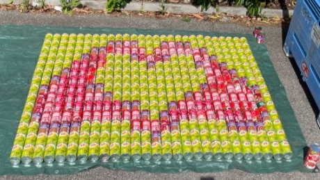 yellow and red cans forming a love heart image on a green drop sheet