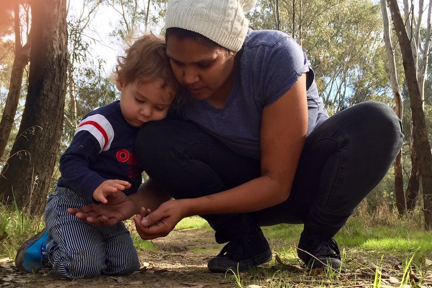 Woman in beanie and little boy look at something from the ground