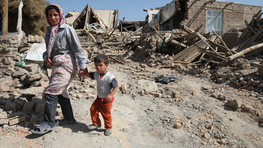 Iranians walk amongst rubble after deadly earthquakes