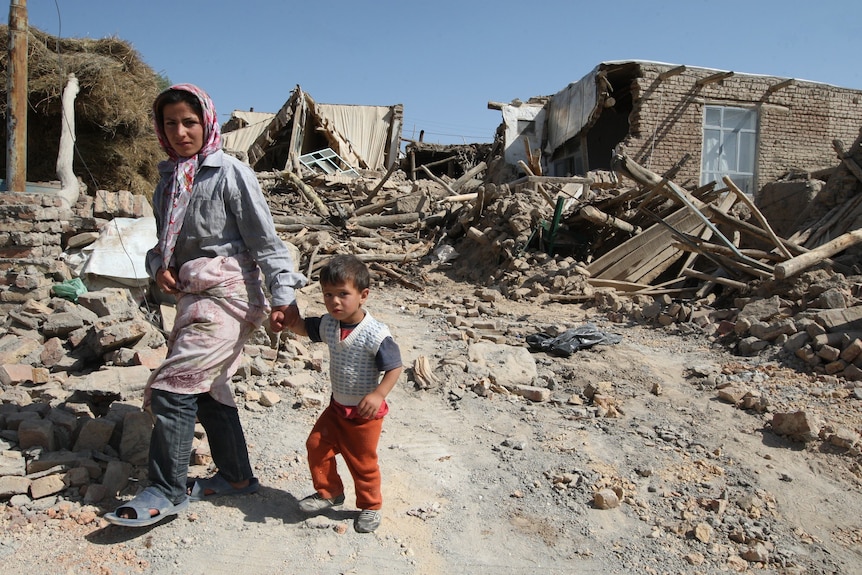 Iranians walk amongst rubble after deadly earthquakes