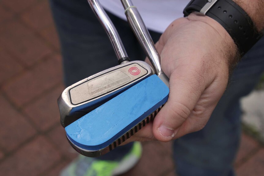 A close-up shot of minigolf putters, one side is coated in rubber.