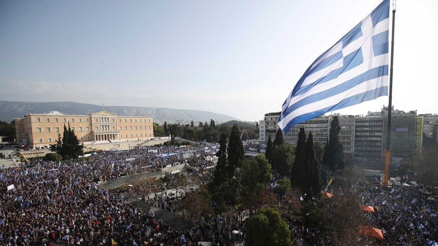 A giant Greek flag hangs from a crane waves over protesters during a rally in Athens.