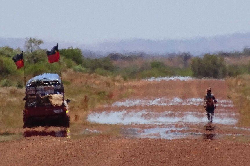 A heat mirage obscures Clinton Pryor and a support vehicle on an outback road.
