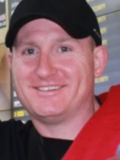 Daniel O’Shea is shown smiling, wearing a black baseball cap and holding a bottle of water.