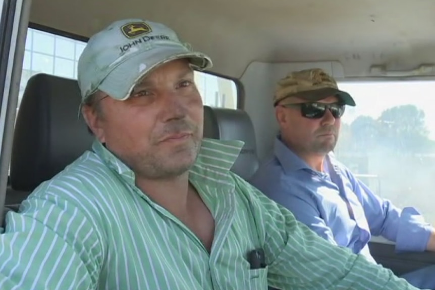 Two men sit inside a ute.