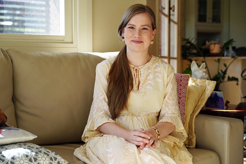 A smiling woman sitting on a sofa.