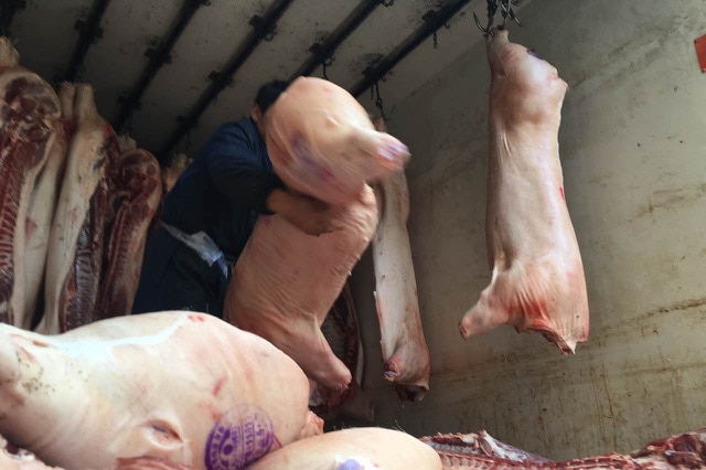 Meat is thrown into storage at a meat market in Zhidan, Shaanxi province, China