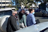 People in COVID masks outside a court building