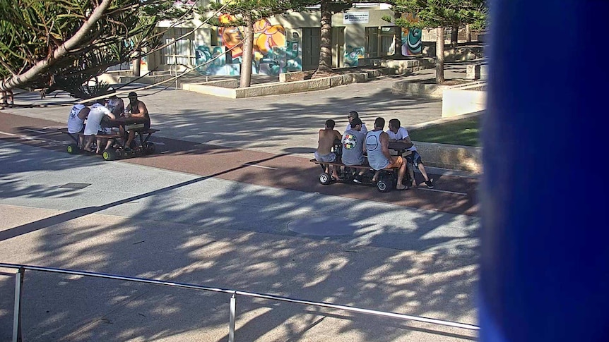 Nine men ride motorised picnic tables in the Scarborough Beach area