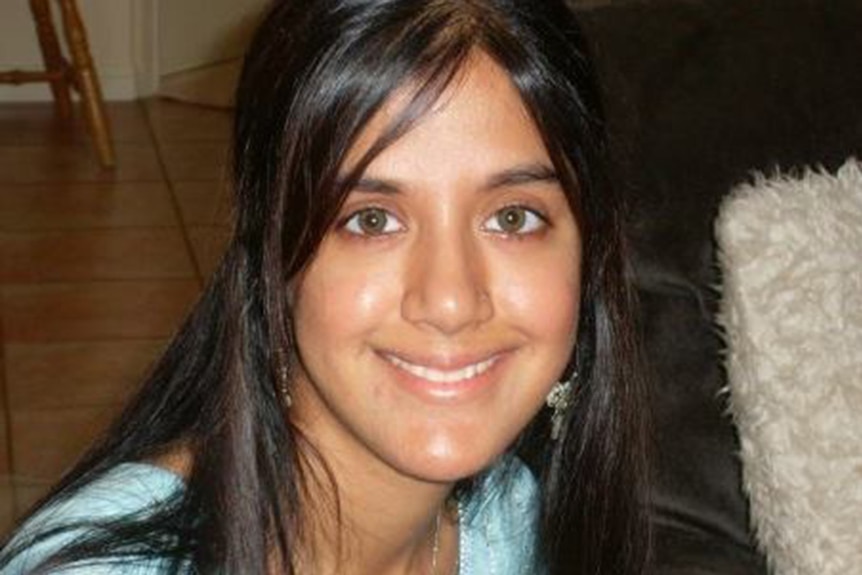 A headshot of a young woman with long black hair in a house.