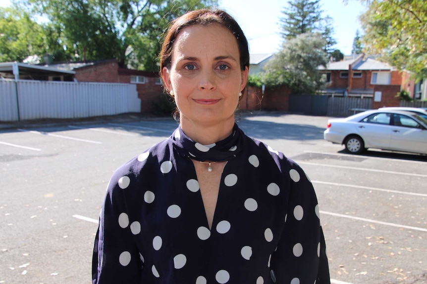 A woman stands in a car park.