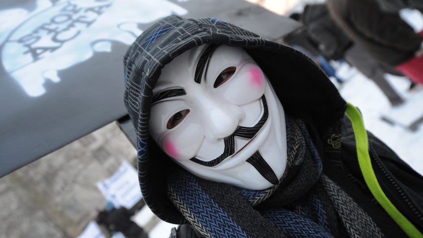 A protester wearing an Anonymous Guy Fawkes mask takes part in a demonstration