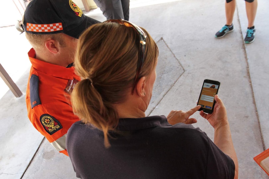 SES staff look at the screen of an iphone which has the SES mobile app