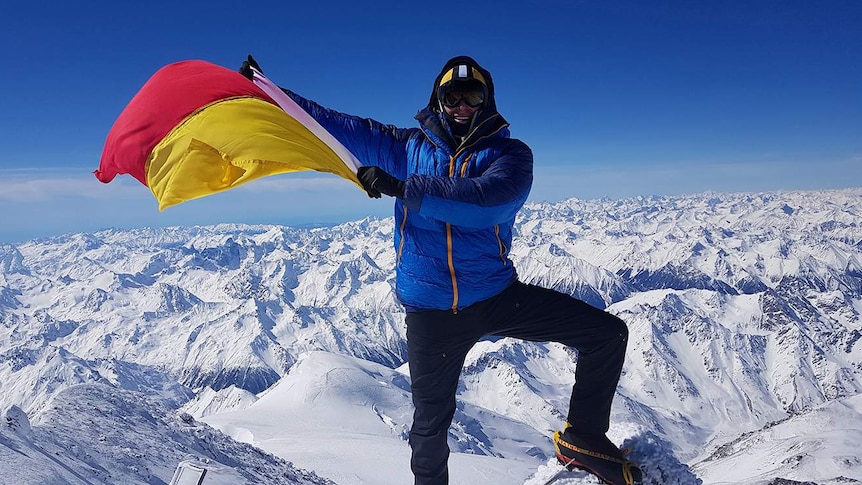 Perth man Steve Plain flies a surf life saving flag on the top of Mount Elbrus.