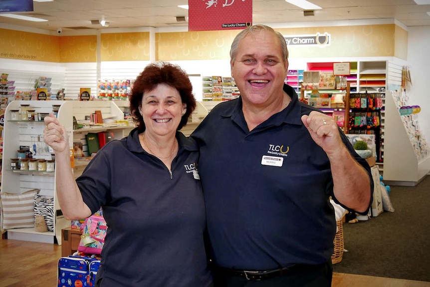 Newsagency owners Annette and Morris Peluchetti stand inside their shop and cheer after eight months of flood restoration