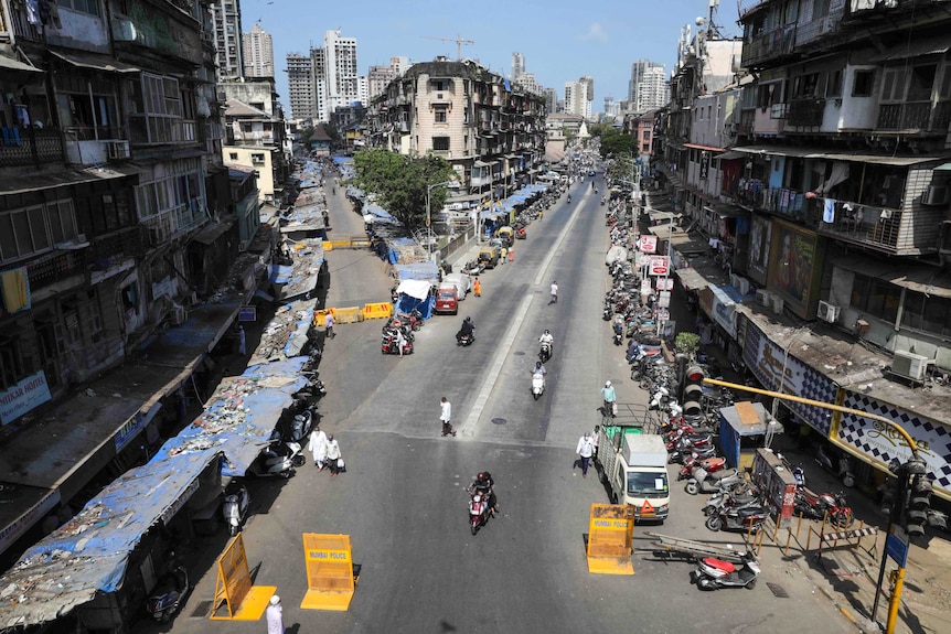 A man on a scooter at a road block on an empty street