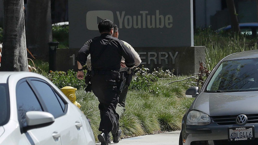 Officers run toward a YouTube office in San Bruno.