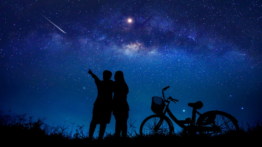 silhouette of man and woman and bike against a night sky with stars