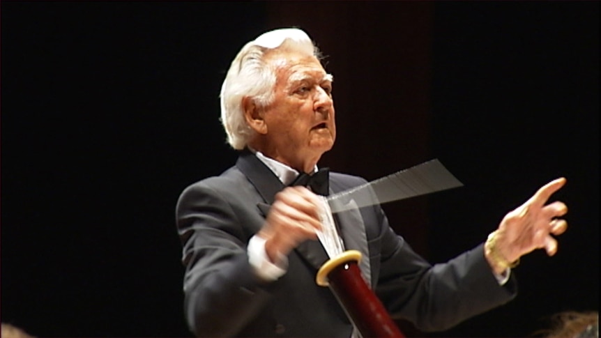 Former Australian Prime Minister Bob Hawke in a tuxedo with a raised conducting baton.