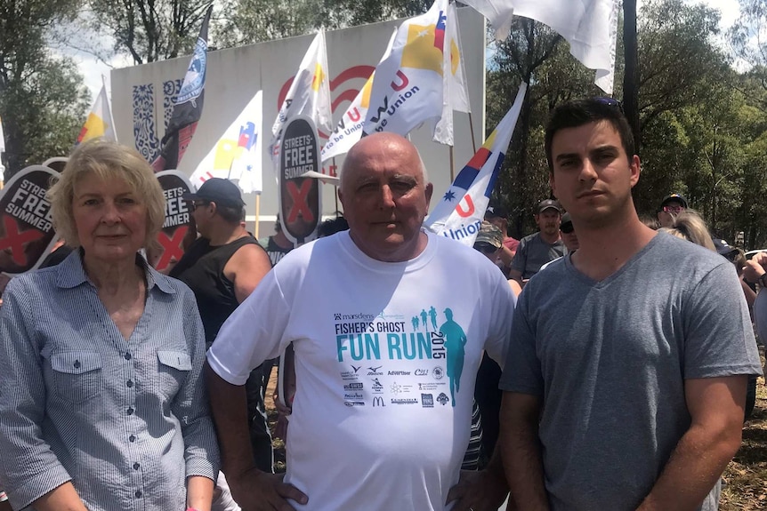 Three people standing in front of union banners calling for a boycott of Streets ice cream.