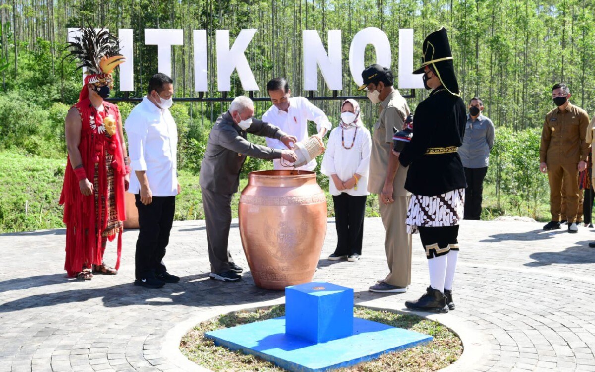 Indonesian president Joko Widodo standing next to his wife while pouring a jug as part of a Javanese ritual.