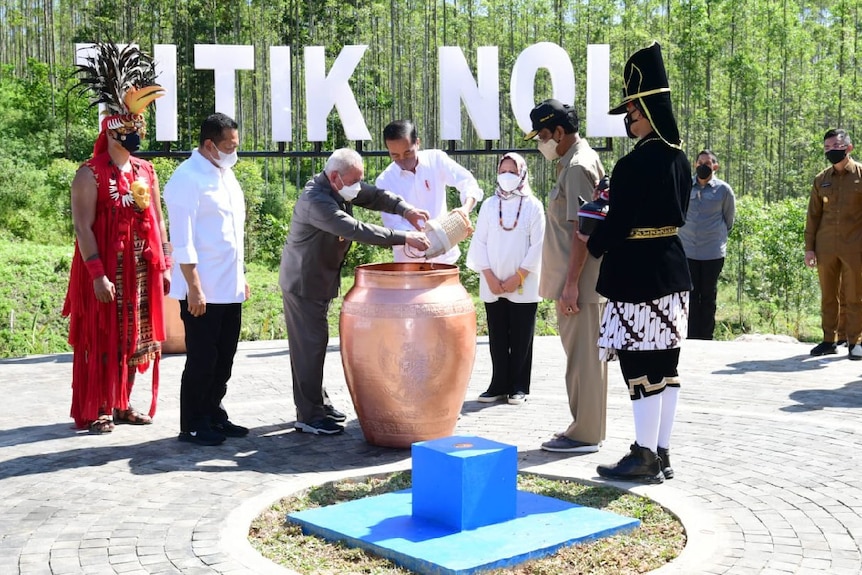 Indonesian president Joko Widodo standing next to his wife while pouring a jug as part of a Javanese ritual.