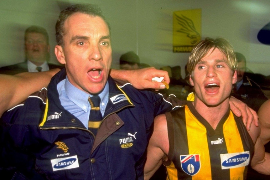 Ken Judge, arms linked, sings the club song along with Shane Crawford in the dressing rooms after a Hawthorn victory.