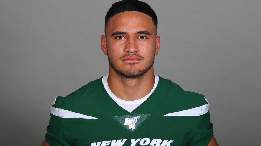 Valentine Holmes in New York Jets gear stares straight at the camera while standing in front of a blank background.