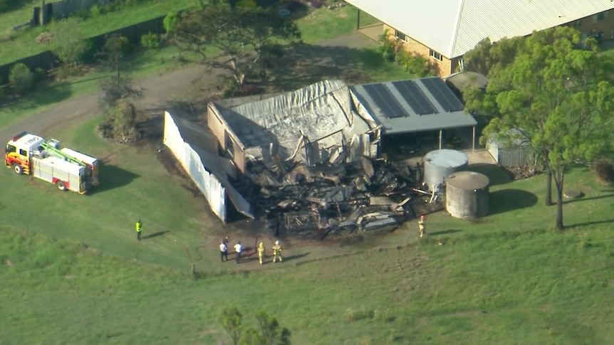 overhead image of a burnt out shed with emergency crews standing nearby