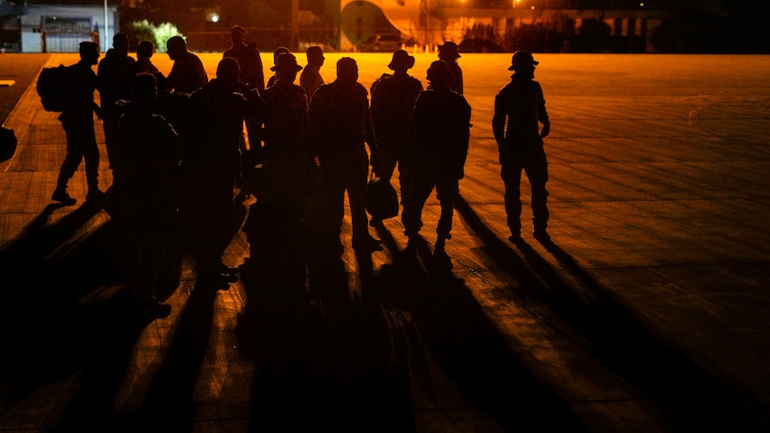 Silhouettes of Saudi soldiers gathered at Port Sudan airport with the sunset behind them