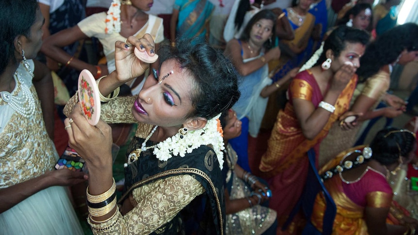 A transgender woman applying make up.