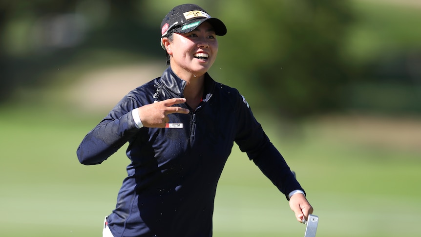Women smiling while throwing up a peace sign during a golf tournament