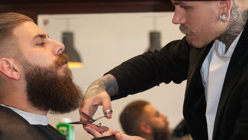 A barber trims a man's beard