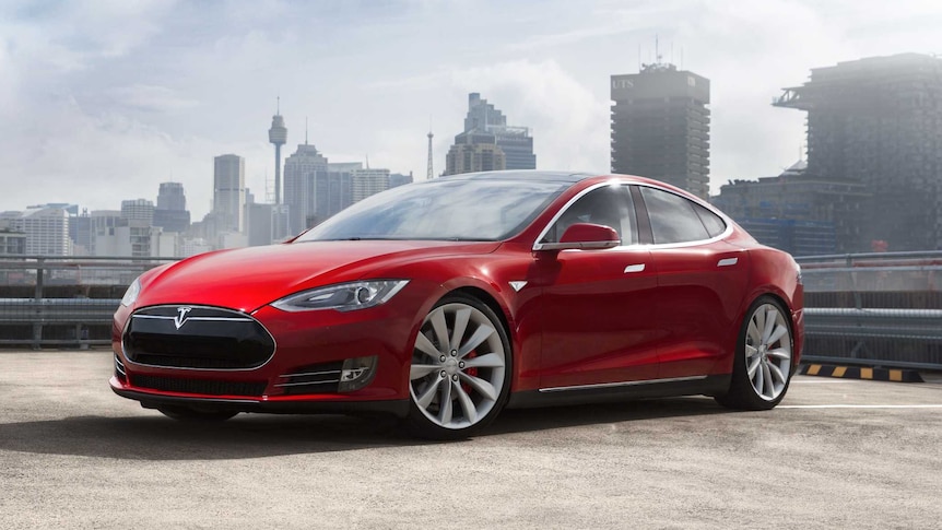 A marketing photo of a slick red car, photographed on a rooftop with the Sydney city skyline in the background.