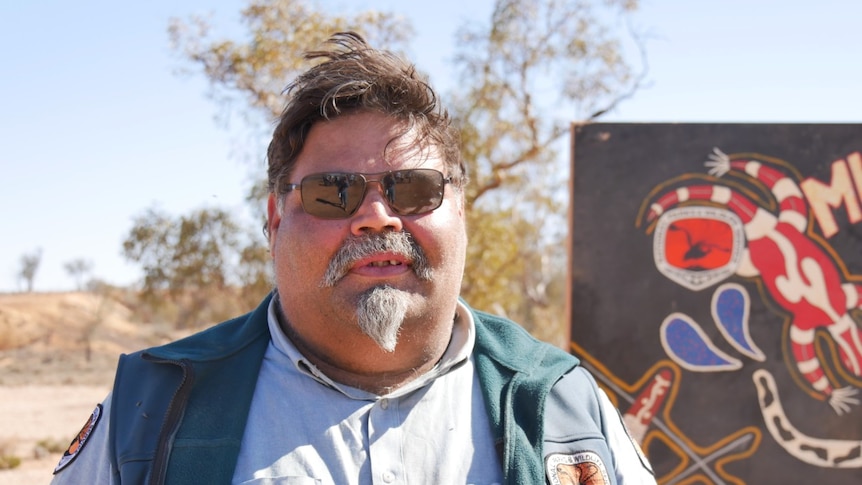 An aboriginal man in sunglasses smiles at the camera.