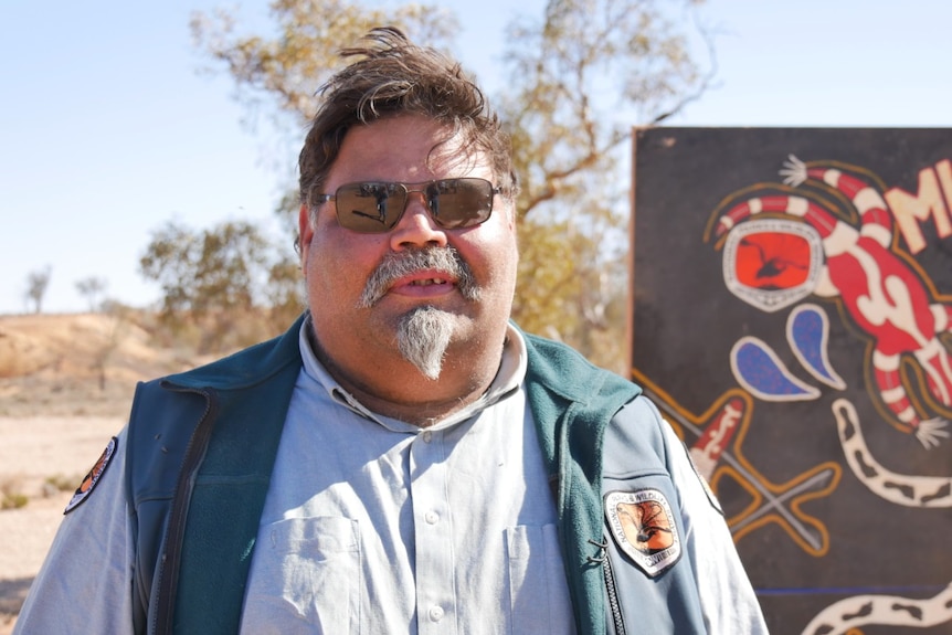 An aboriginal man in sunglasses smiles at the camera.