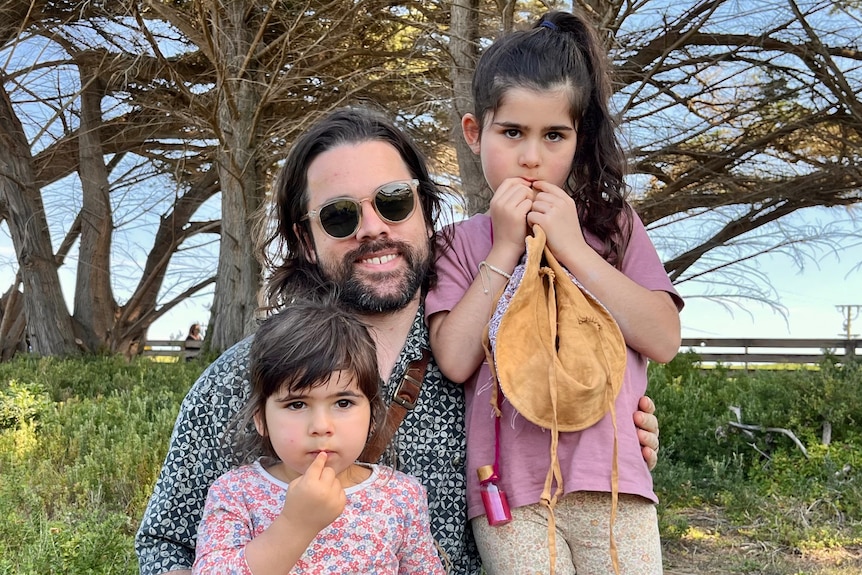 a father and his two young daughters outside.