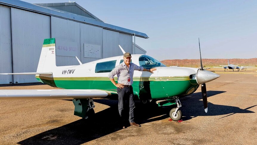 A man standing by a small plane
