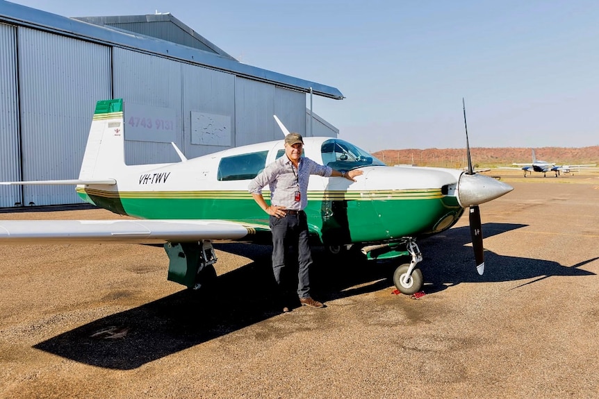 A man standing by a small plane