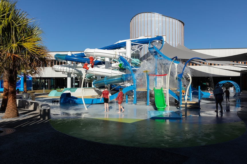 A modern aquatic facility with slides and water fountains.
