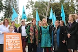 A group of protesters holding flags and a Rethink Perth Freight Link placard