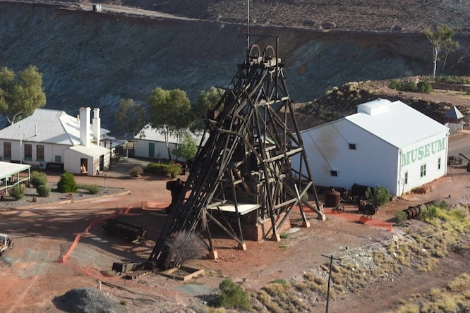 Aerial image of a timber mining headframe with several white buildings surrounding it.