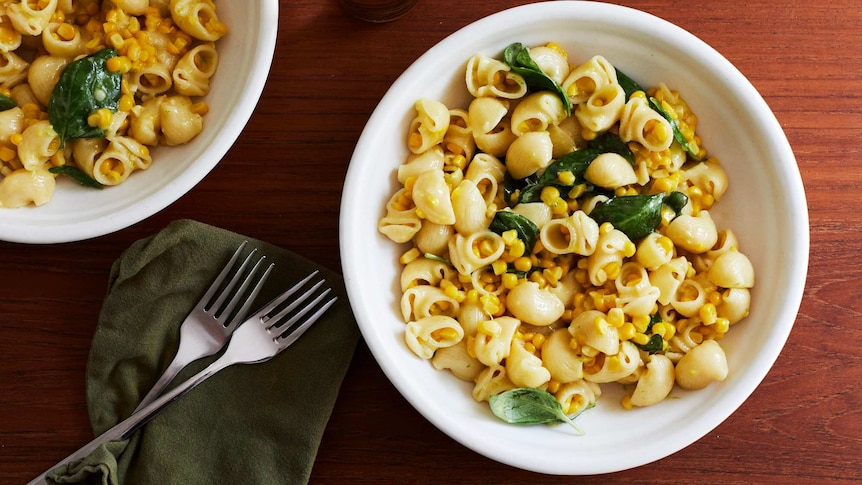 Two bowls of creamy corn pasta with pasta shells, corn kernels, basil and cream, an easy family dinner.