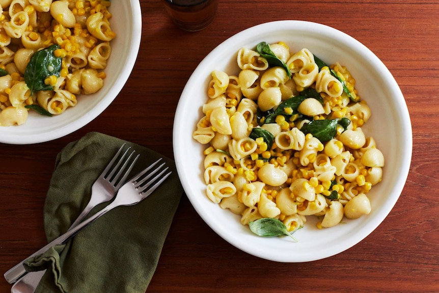 Two bowls of creamy corn pasta with pasta shells, corn kernels, basil and cream, an easy family dinner.