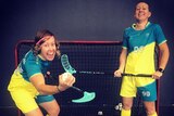 Two women smile for the camera while in floorball uniform