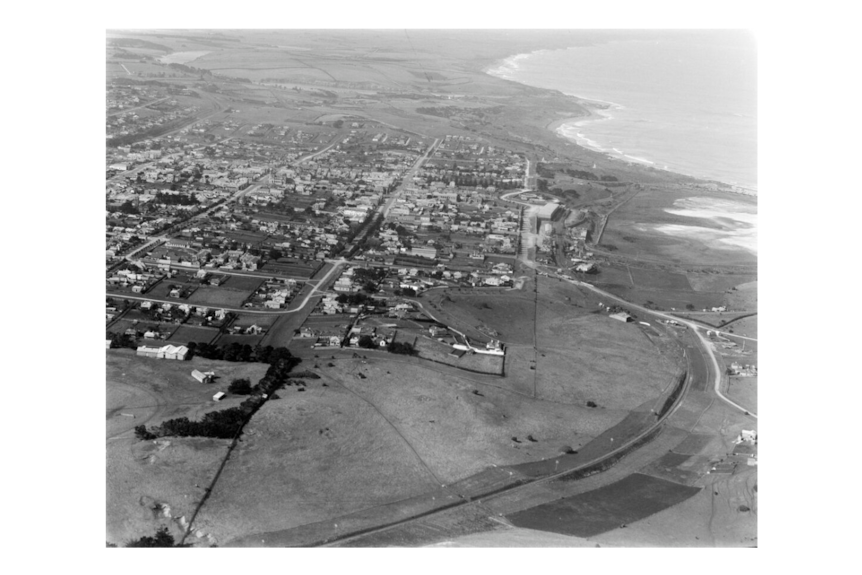 A black and white aerial photograph of the coastal town of Warrnambool taken between 1925 and 1930.
