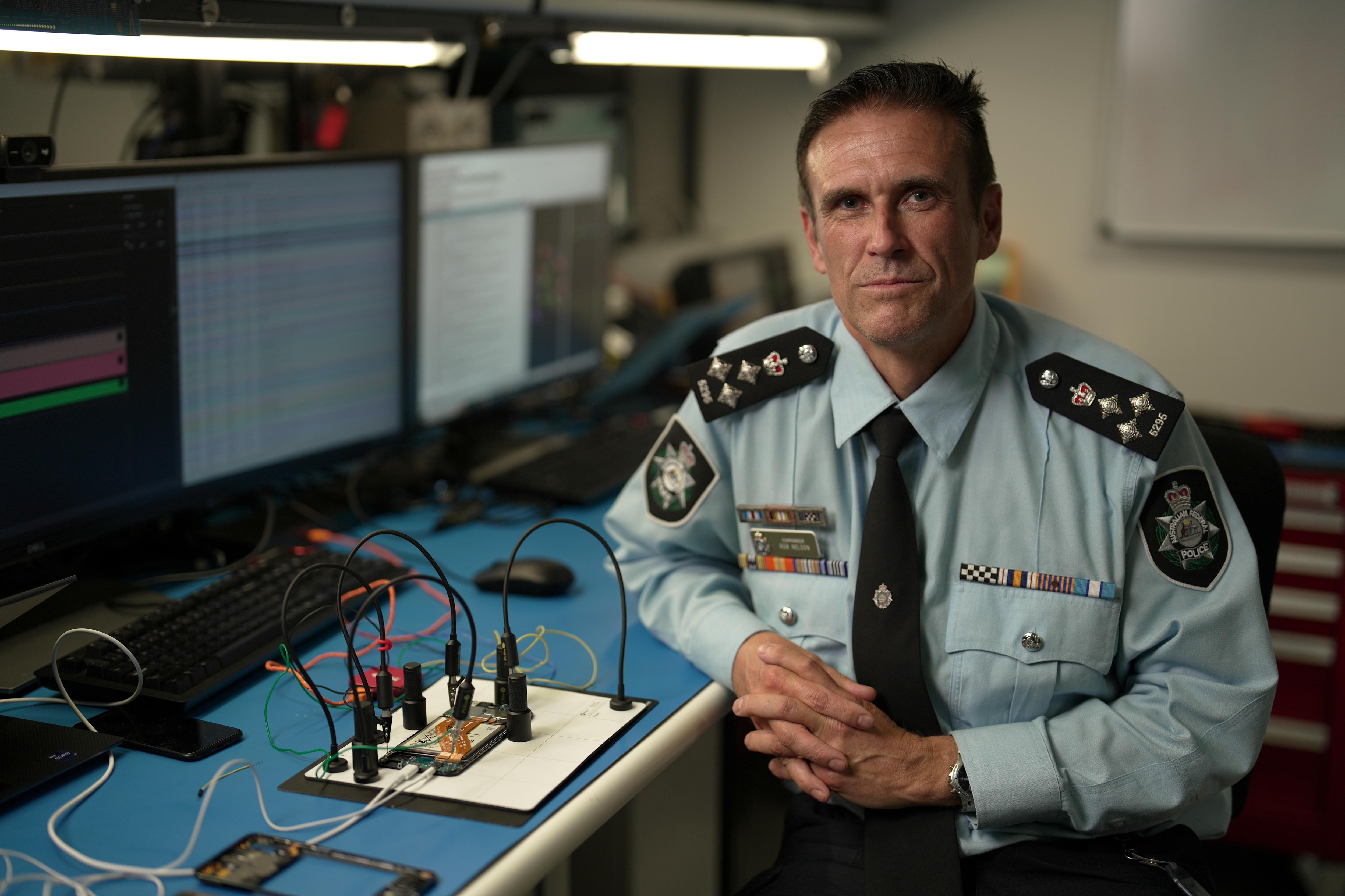 A man wearing a police uniform sits at a desk.