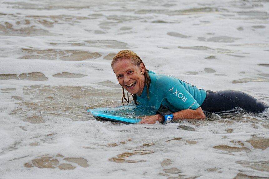 Older woman in blue wetsuit on boogie board.