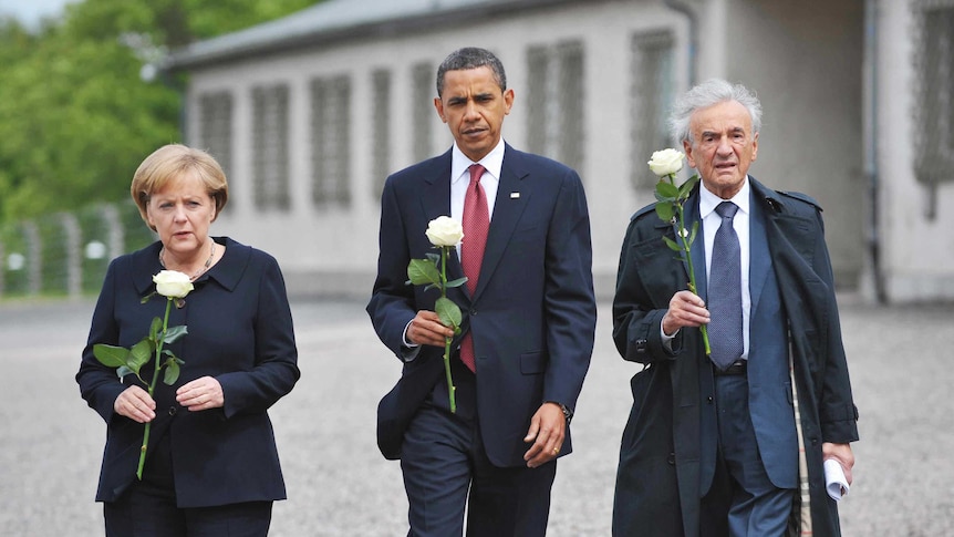 Angela Merkel, Barack Obama and Elie Wiesel hold white roses as they walk together at the Buchenwald concentration camp.