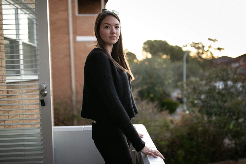 A woman poses on a balcony